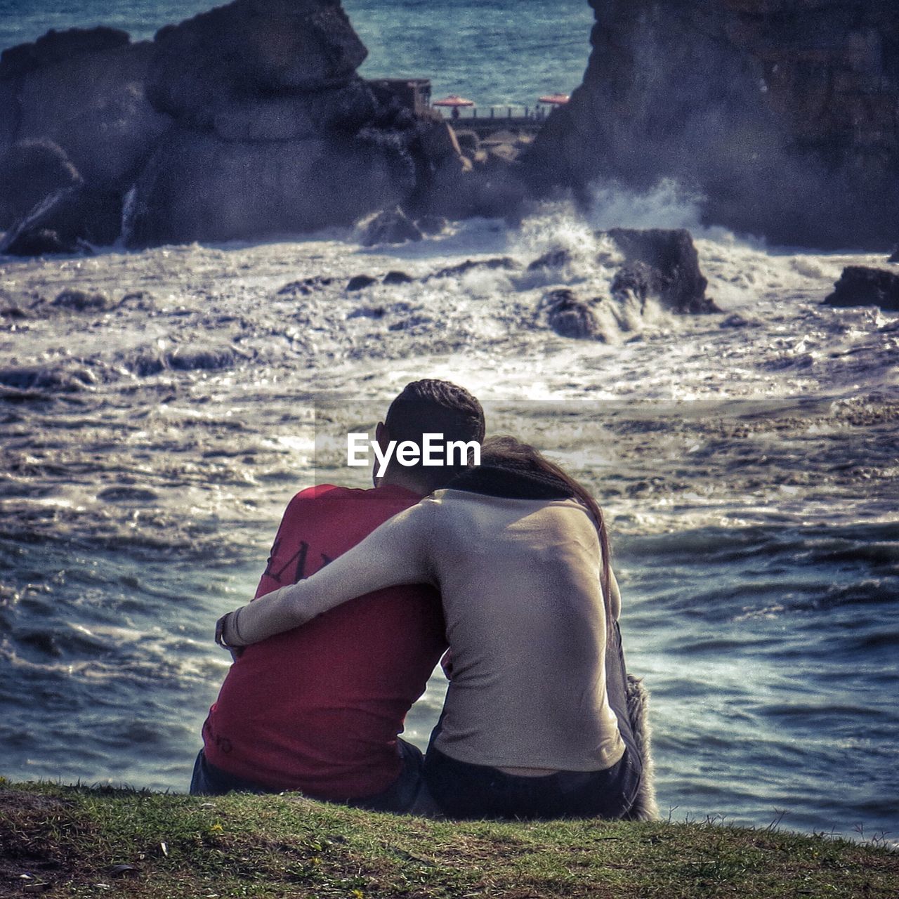 Rear view of couple sitting on river shore