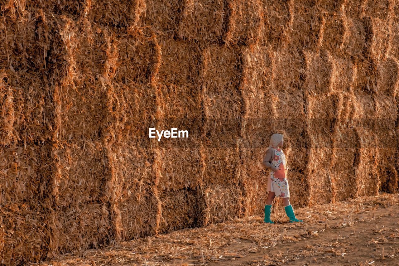 Mid adult woman standing against hay bales