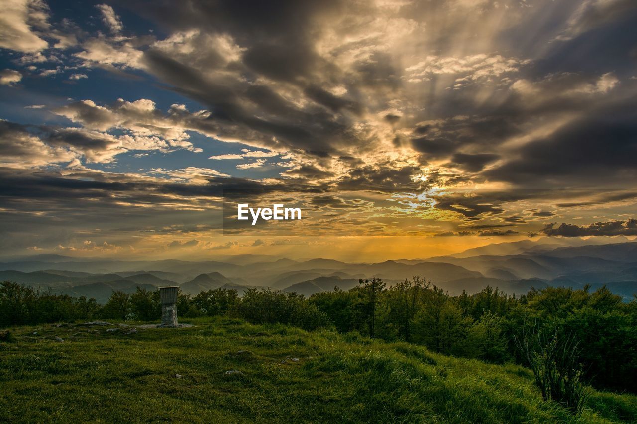 Scenic view of green landscape against sky during sunset