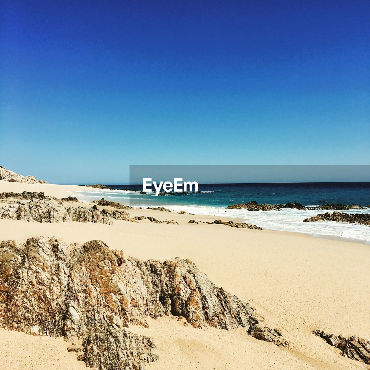 Scenic view of beach against clear blue sky