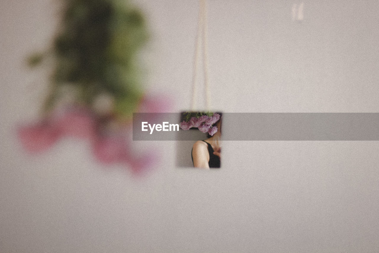 Midsection of woman reflecting on glass against wall