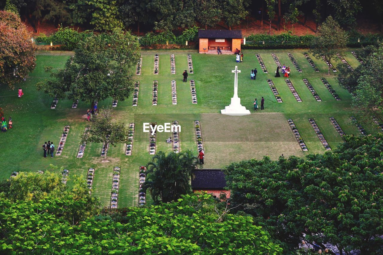 High angle view of people and white cross on field in cemetery