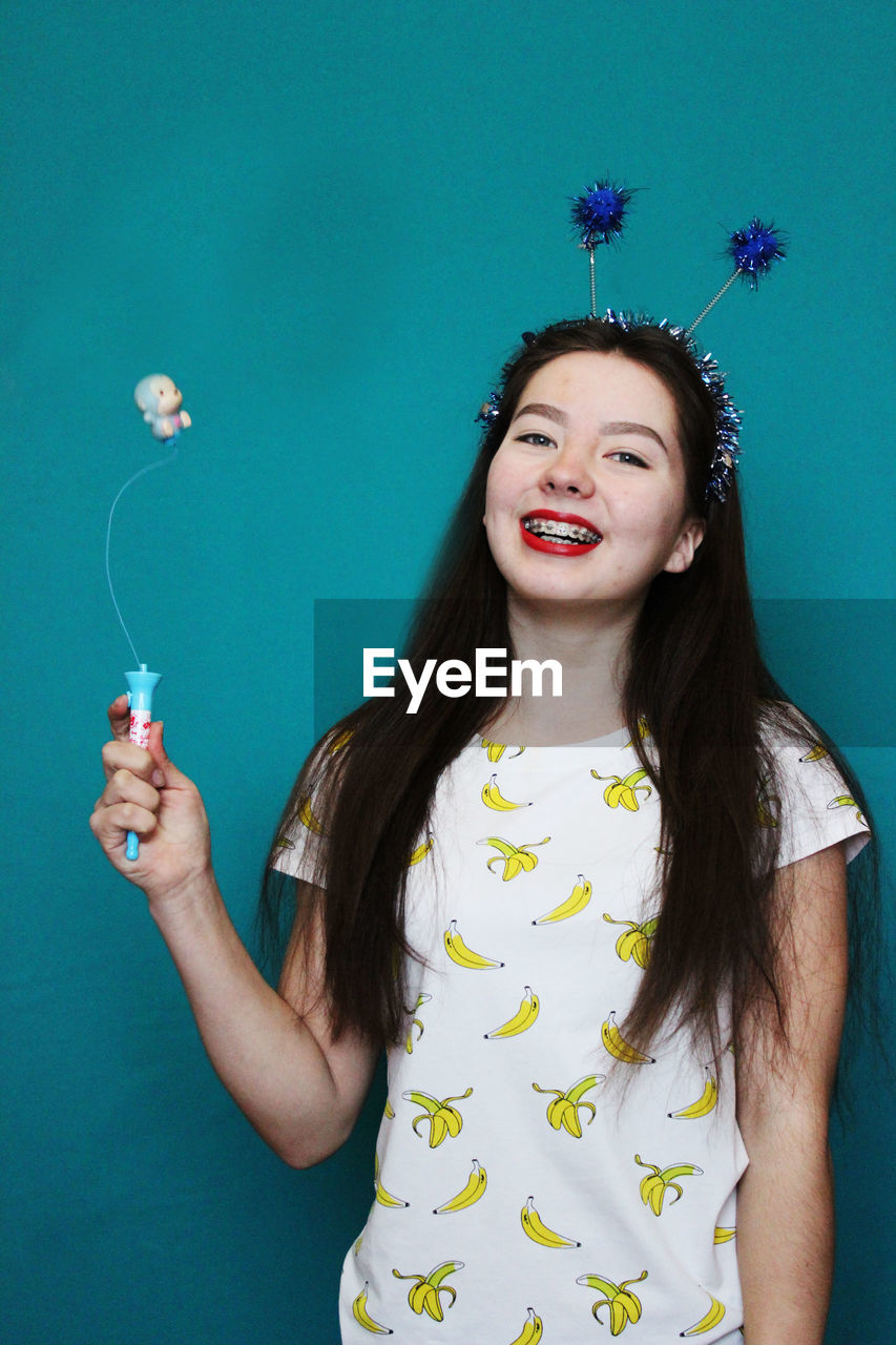 Portrait of happy woman holding toy against blue background