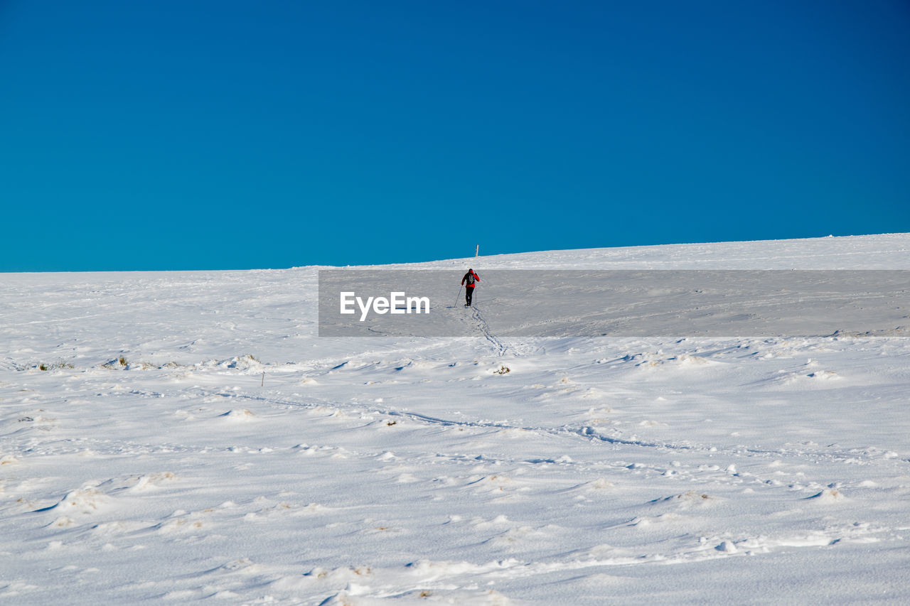 PERSON ON SNOWCAPPED MOUNTAIN AGAINST CLEAR SKY