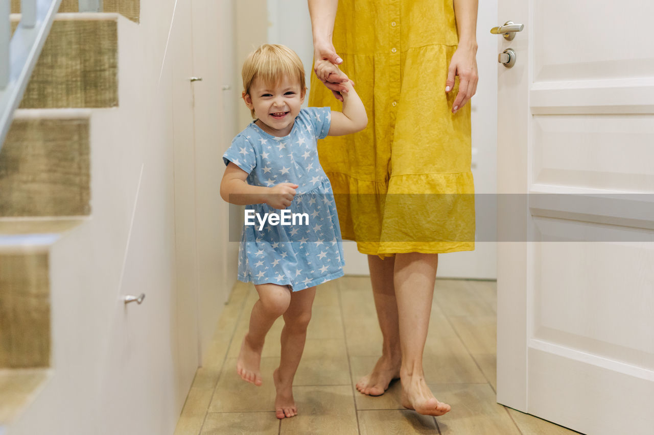 Little emotional daughter has fun at home holding her mother's hand.
