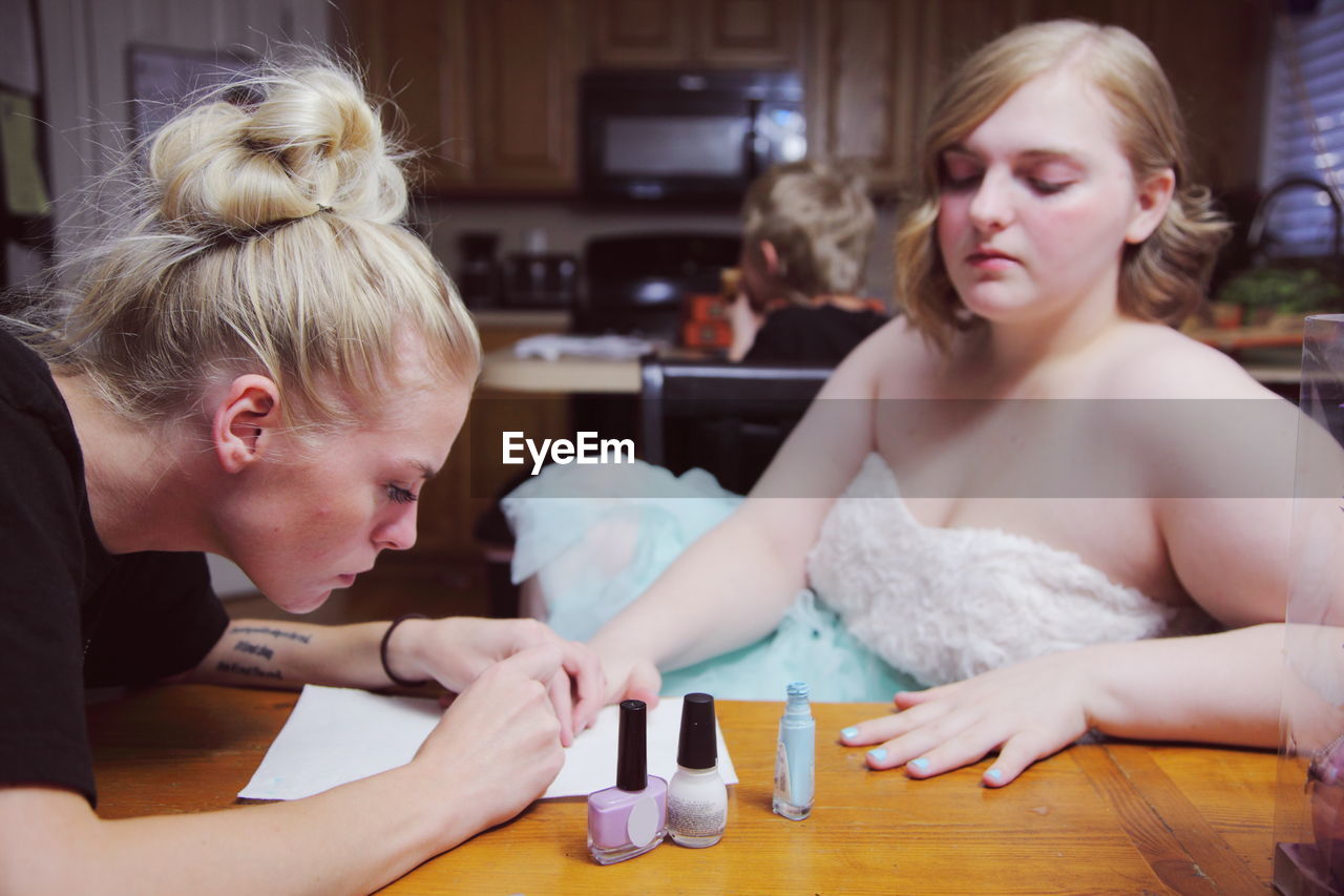 Woman applying nail polish on teenage girl hand at home