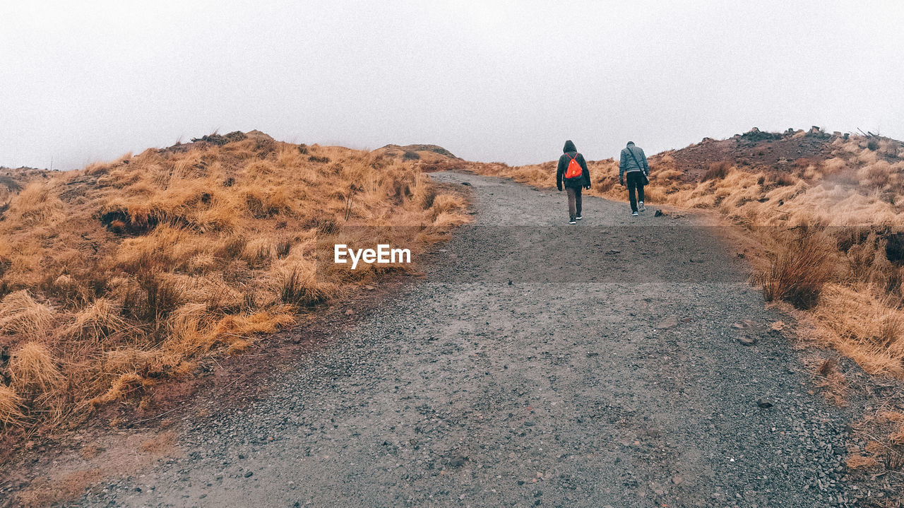 Rear view of people walking on mountain against sky