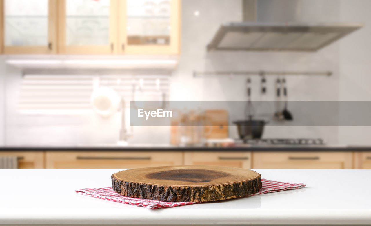 Empty cutting board on a wooden table and blurred kitchen background