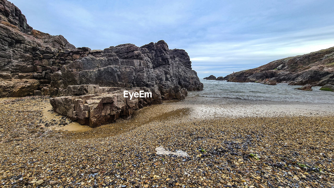 ROCK FORMATIONS ON SHORE AGAINST SKY