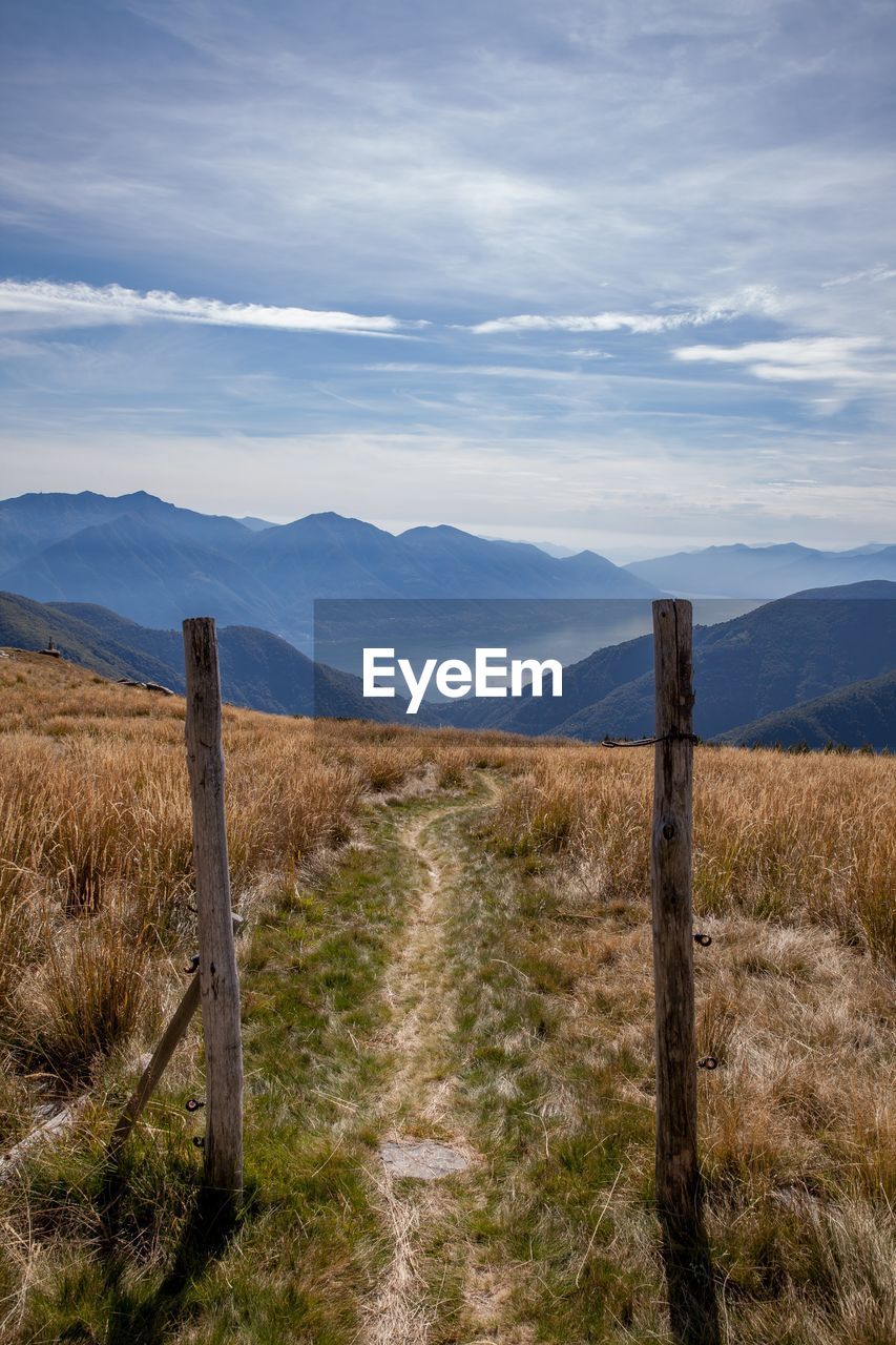 WOODEN POST ON FIELD AGAINST SKY