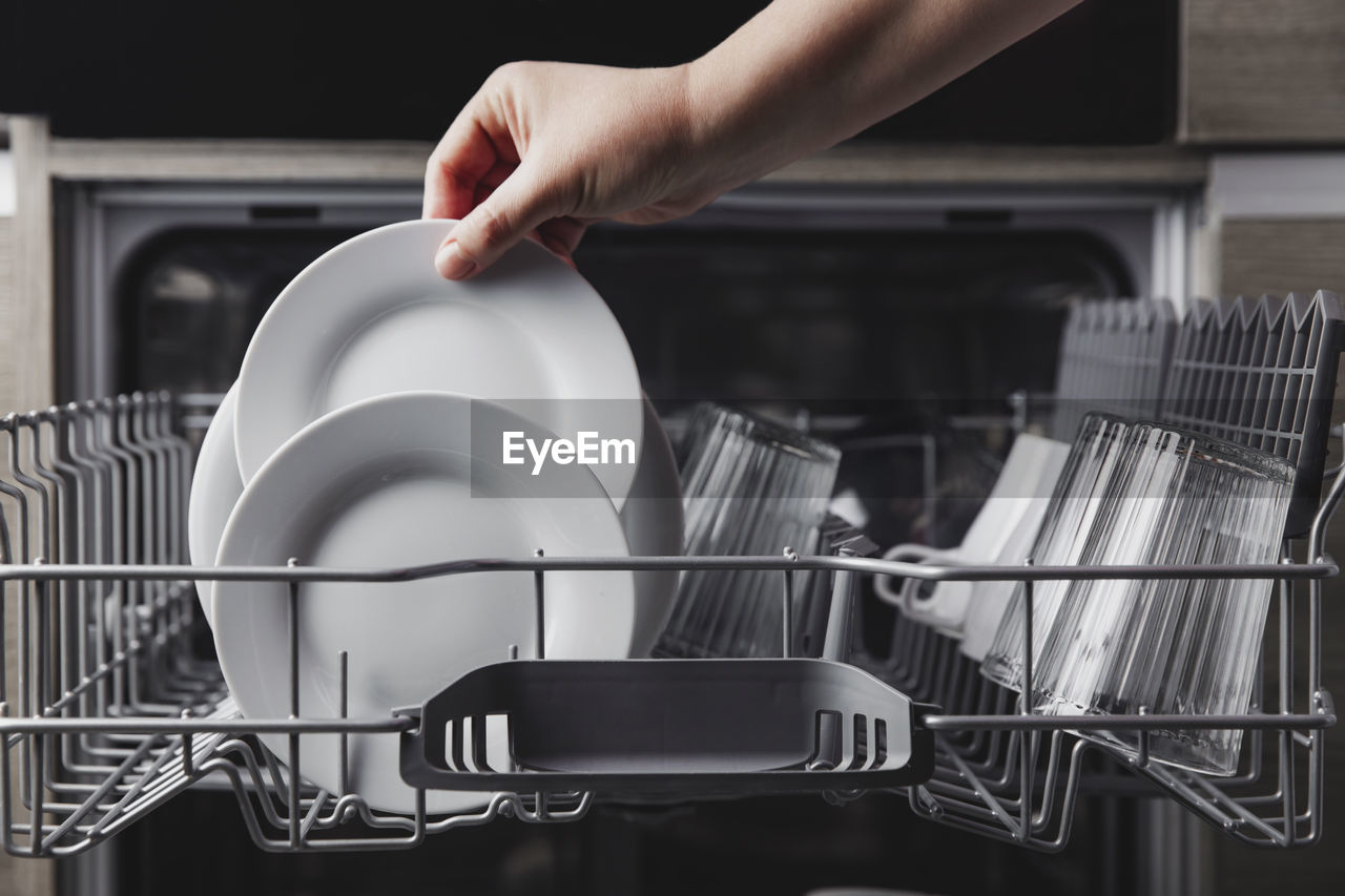 Woman puts a plate in the dishwasher or takes from it. housewife does her housework