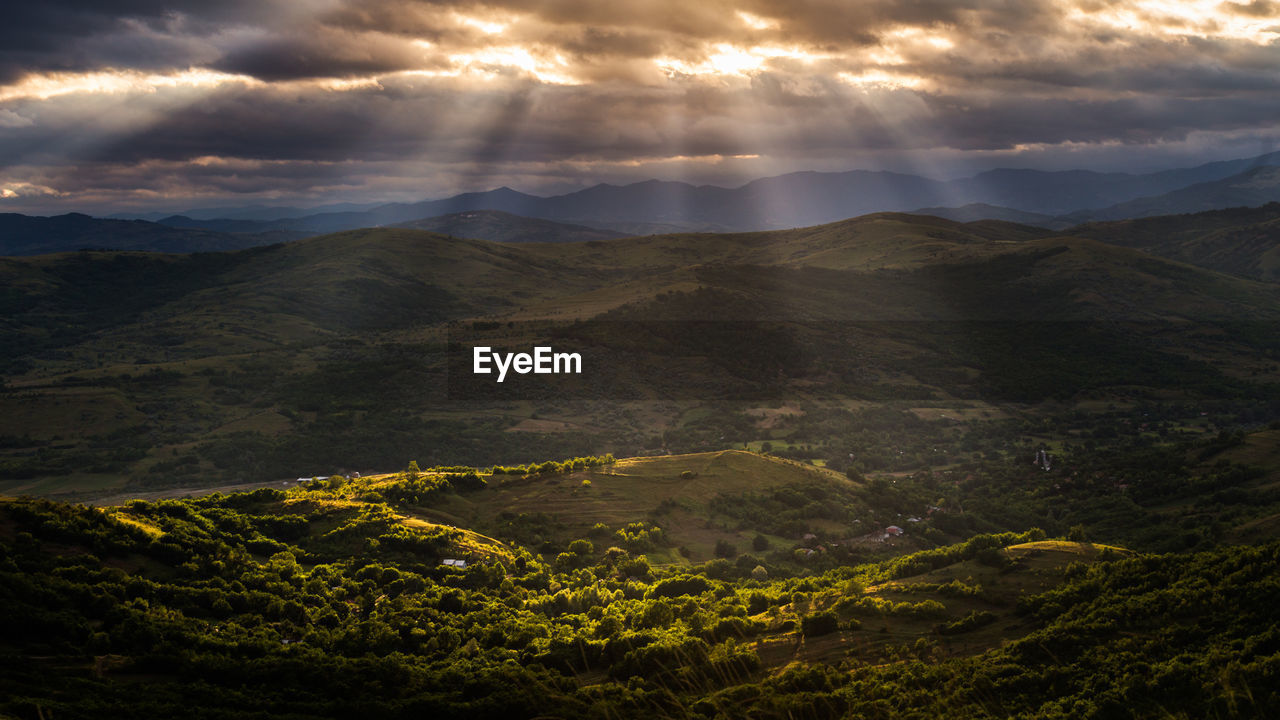 Scenic view of mountains against cloudy sky during sunset