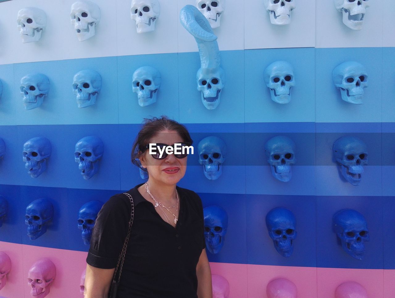 Portrait of woman in sunglasses standing against wall