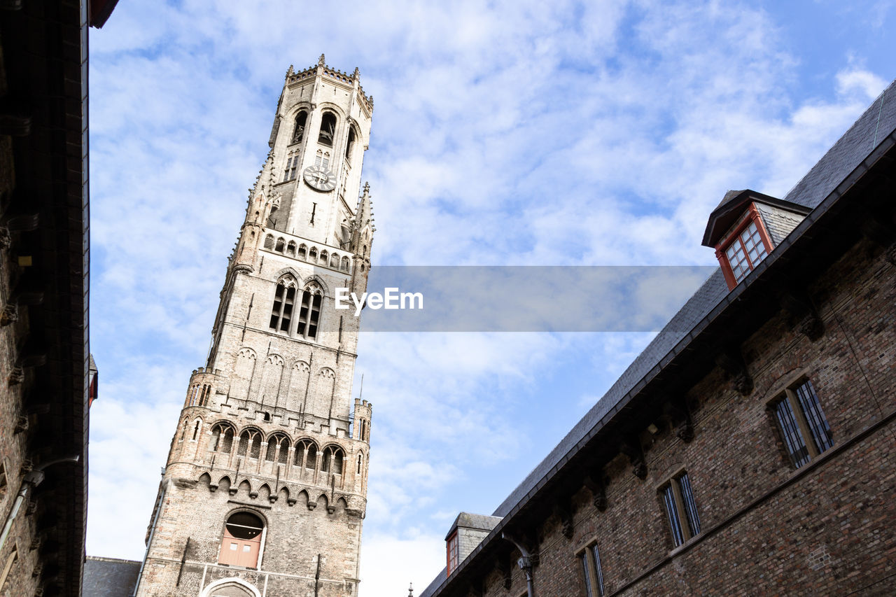 Belfry of bruges against blue sky and white cloud