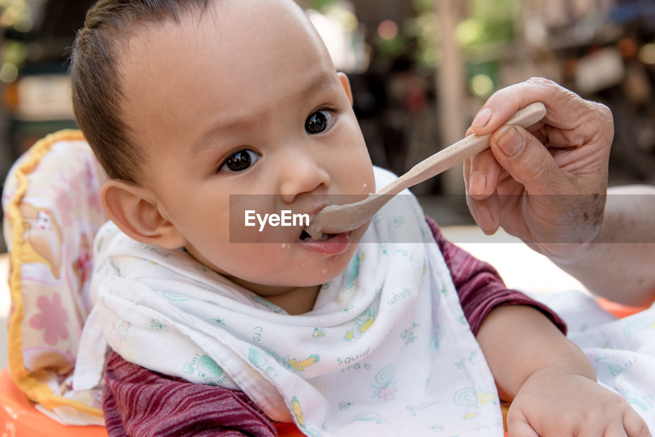 Cropped hand of grandmother feeding grandson