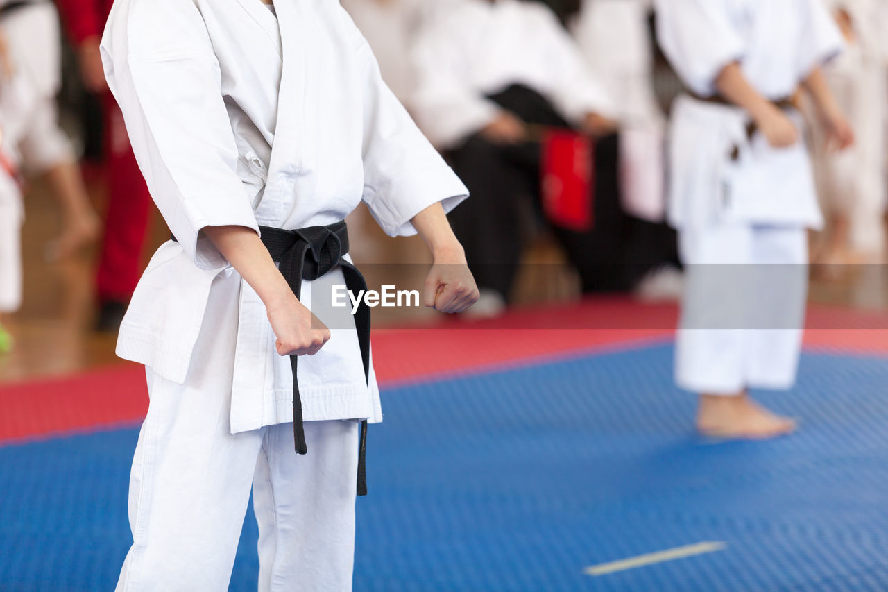 Midsection of man standing on stage during karate competition