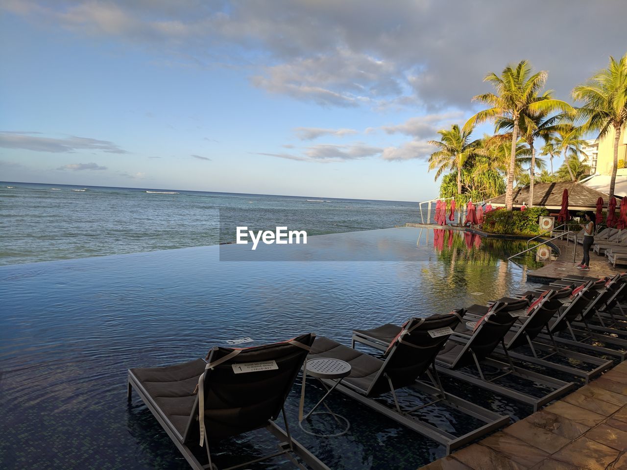 CHAIRS AND TABLE ON BEACH AGAINST SKY