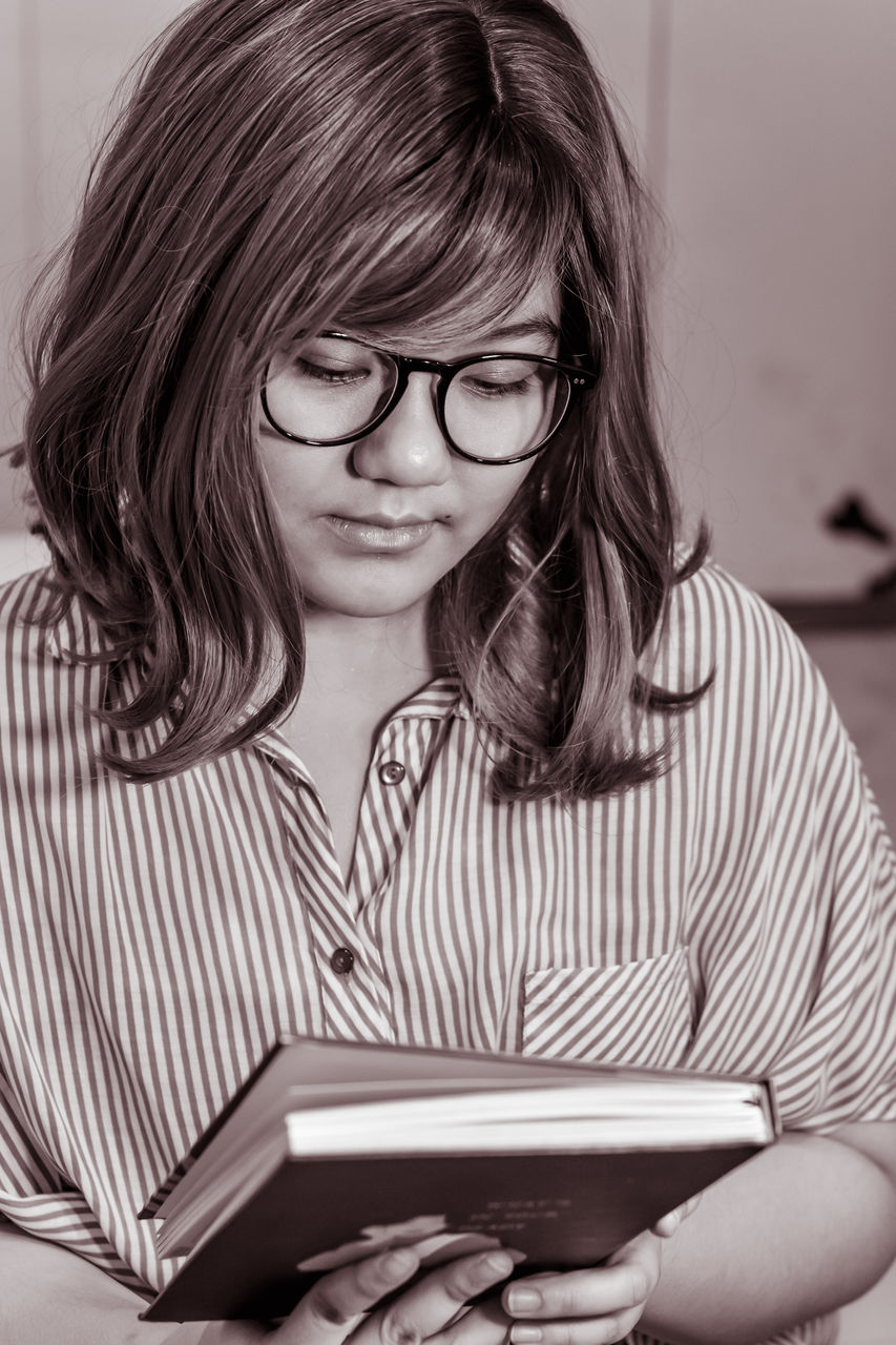 glasses, one person, eyeglasses, women, vision care, black and white, education, learning, child, adult, reading, publication, student, book, female, hairstyle, indoors, portrait, monochrome, portrait photography, person, childhood, casual clothing, intelligence, white, monochrome photography, looking, studying, looking down, black, front view, long hair, young adult, activity, striped, holding, teenager, sitting, communication, photo shoot, lifestyles, emotion, technology, eyewear