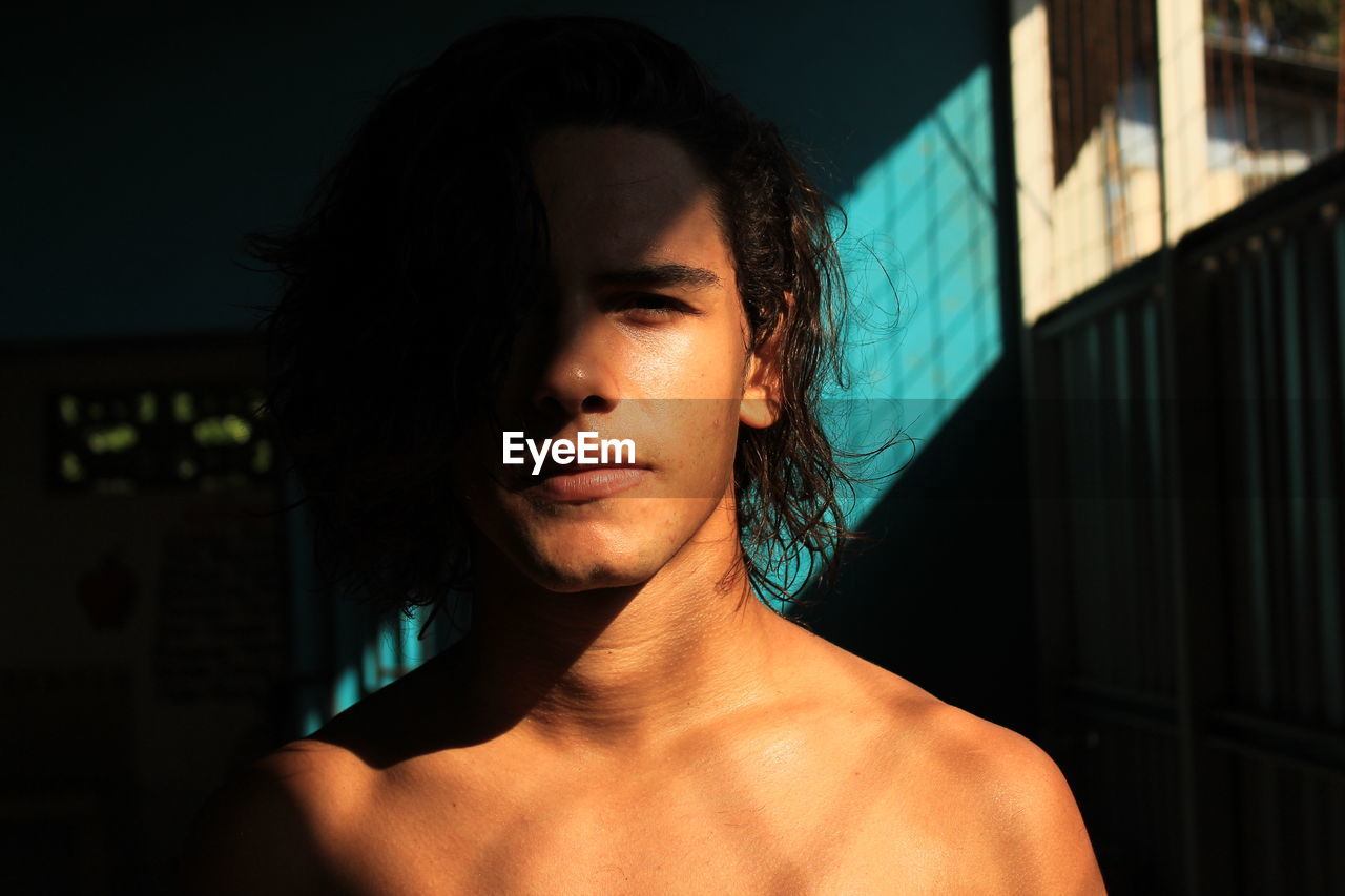 Sunlight falling on shirtless young man at home