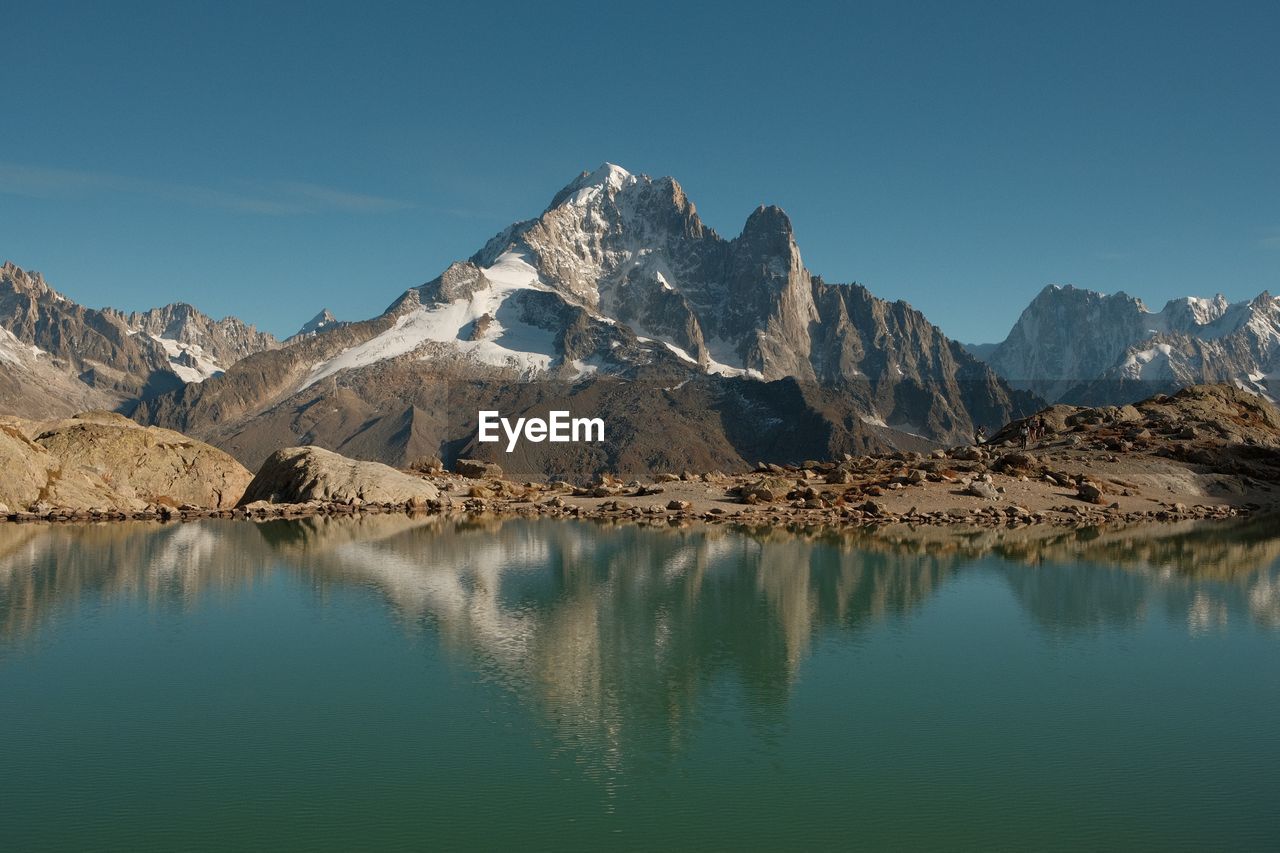 Scenic view of lake by snowcapped mountains against sky