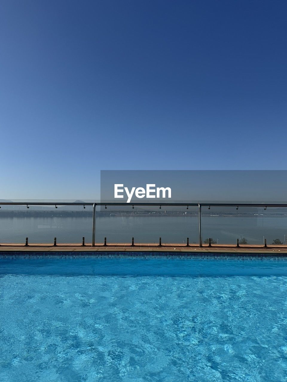 water, blue, sky, ocean, sea, nature, clear sky, horizon, swimming pool, copy space, scenics - nature, beauty in nature, no people, day, tranquility, tranquil scene, outdoors, sunlight, sunny, railing, architecture, wave, vacation, travel destinations, bay, idyllic, travel, waterfront, land, horizon over water, built structure, pier, shore, beach