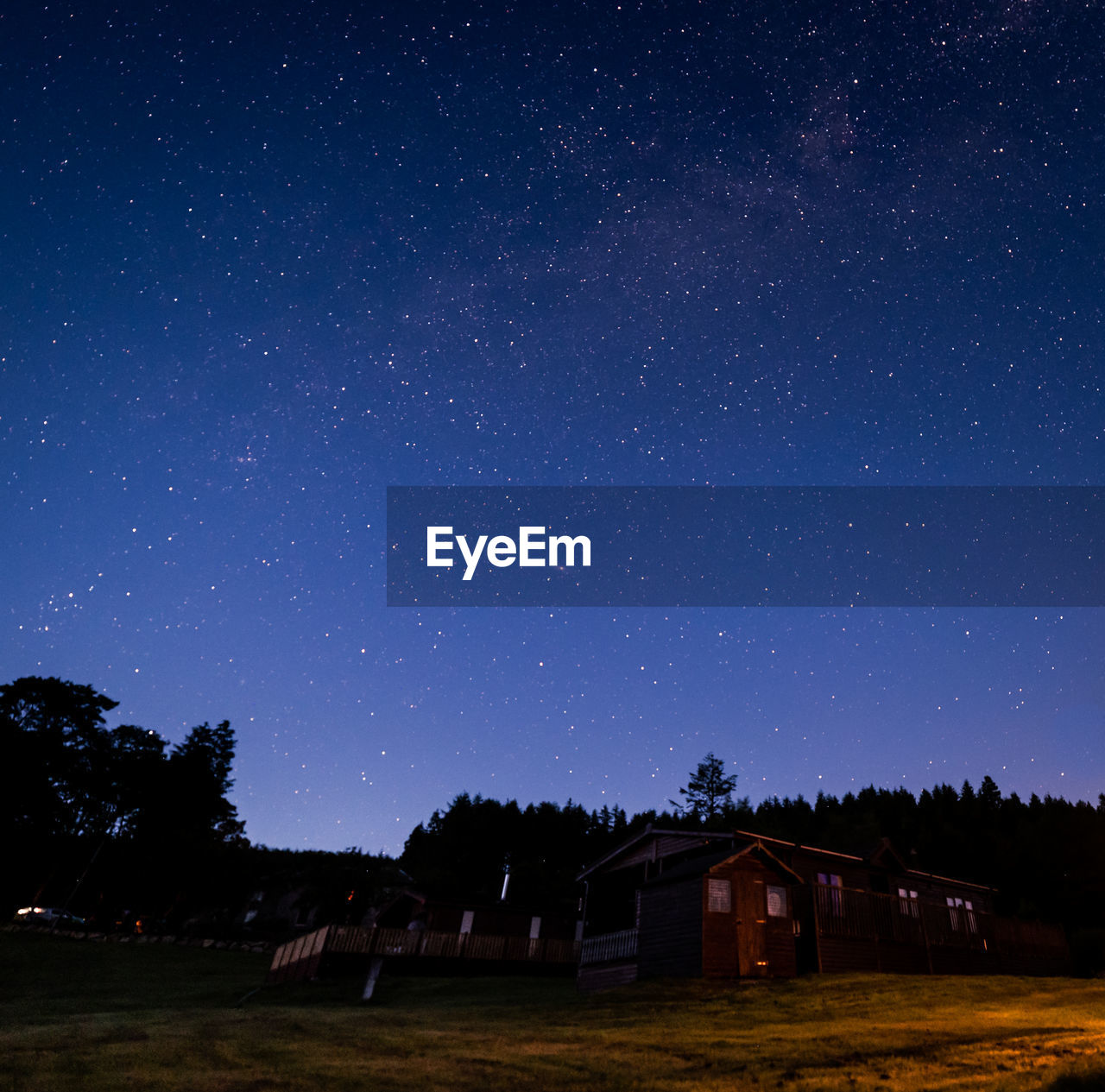 Scenic view of house and trees against sky at night