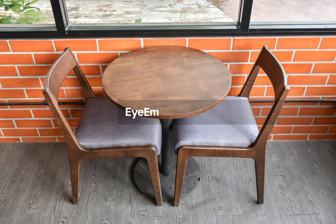 HIGH ANGLE VIEW OF EMPTY CHAIRS AND TABLE AGAINST WALL