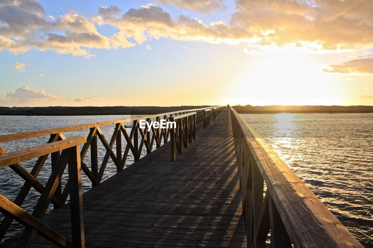 Pier over sea against sky during sunset