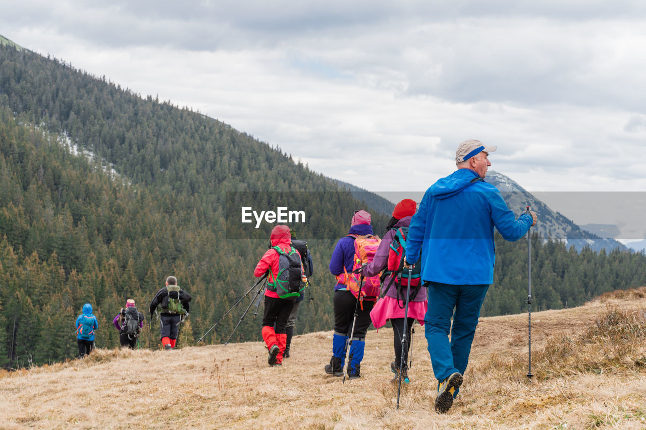 rear view of people walking on mountain against sky