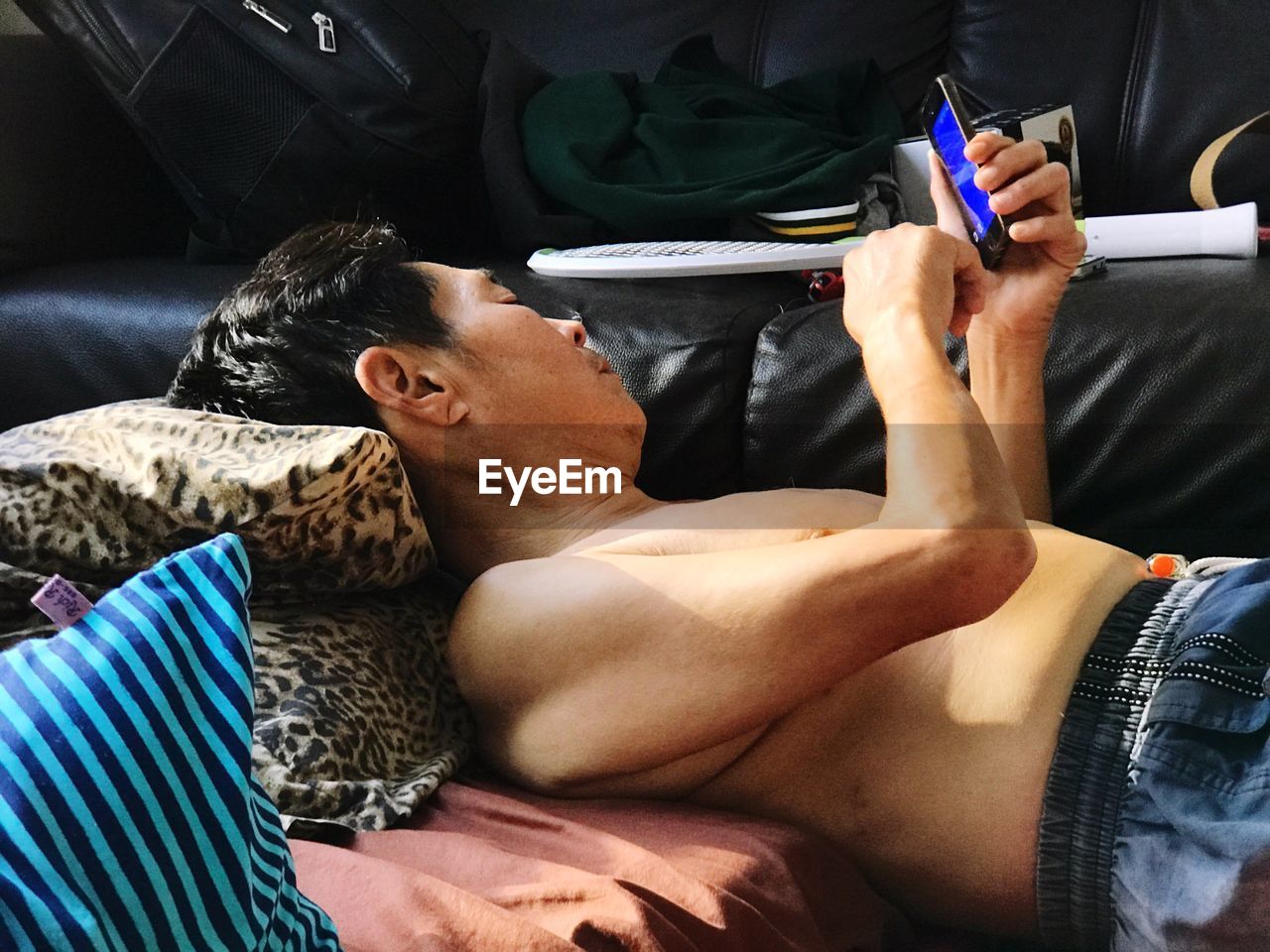 Mature man using mobile phone while resting at home