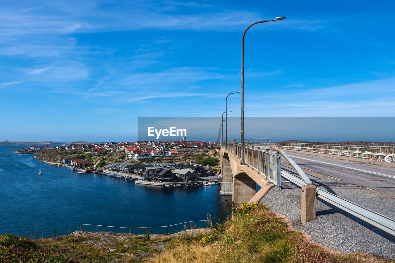 HIGH ANGLE VIEW OF BRIDGE OVER SEA AGAINST BLUE SKY