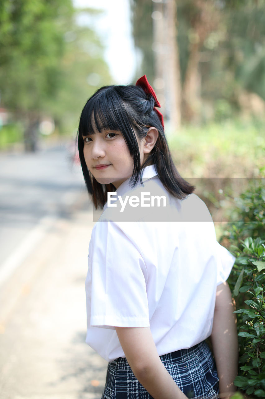 portrait of young woman standing on footpath