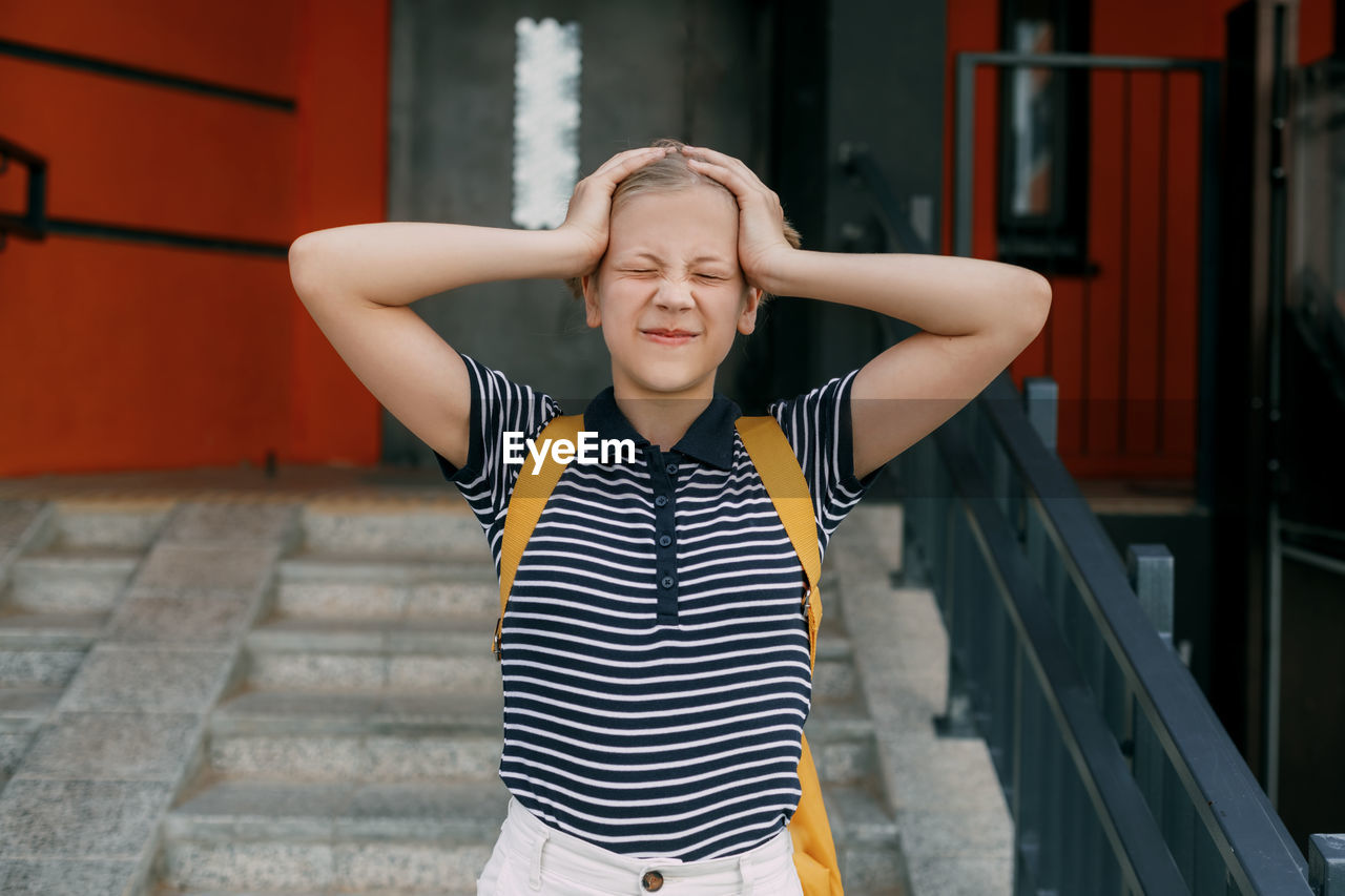 A charming schoolgirl holds her head, can't cope with stress and emotions