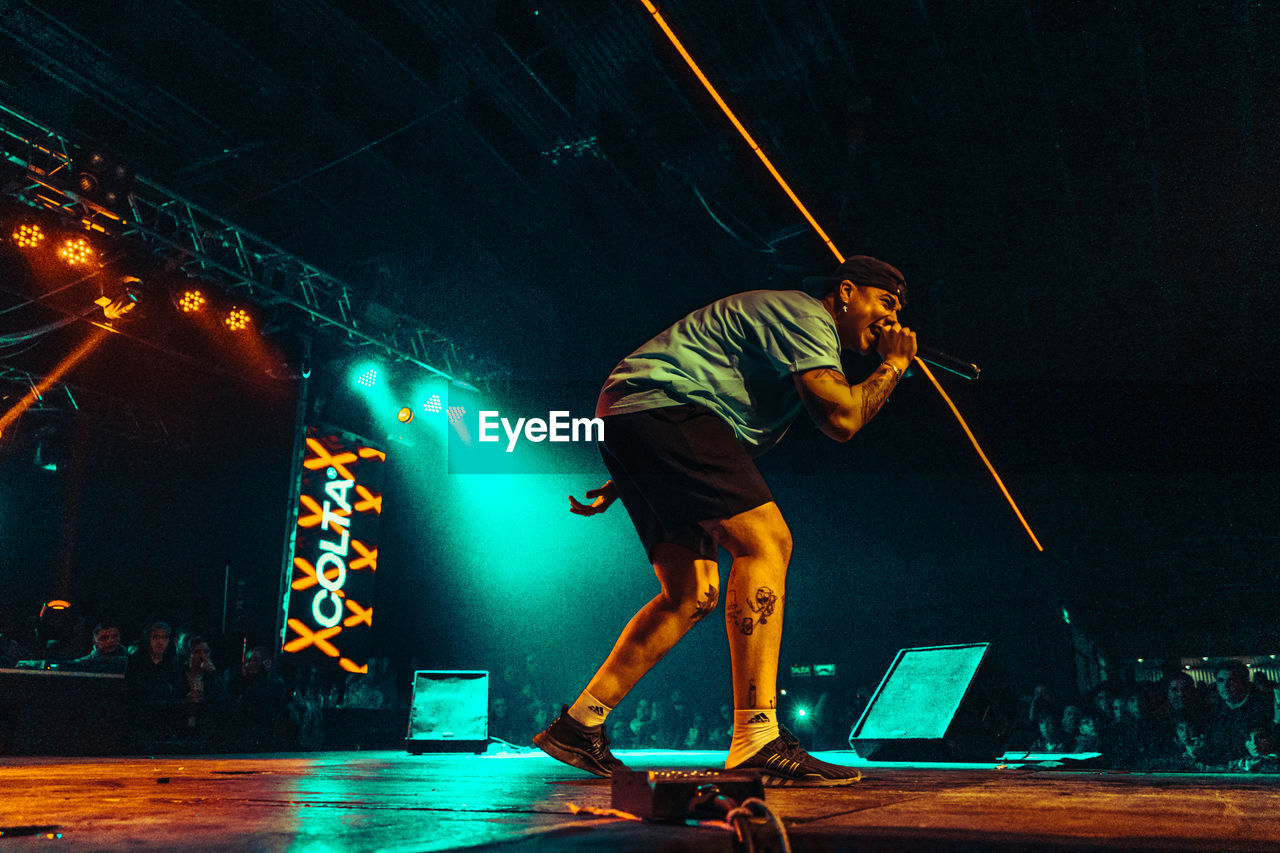 FULL LENGTH OF MAN STANDING AT ILLUMINATED NIGHTCLUB