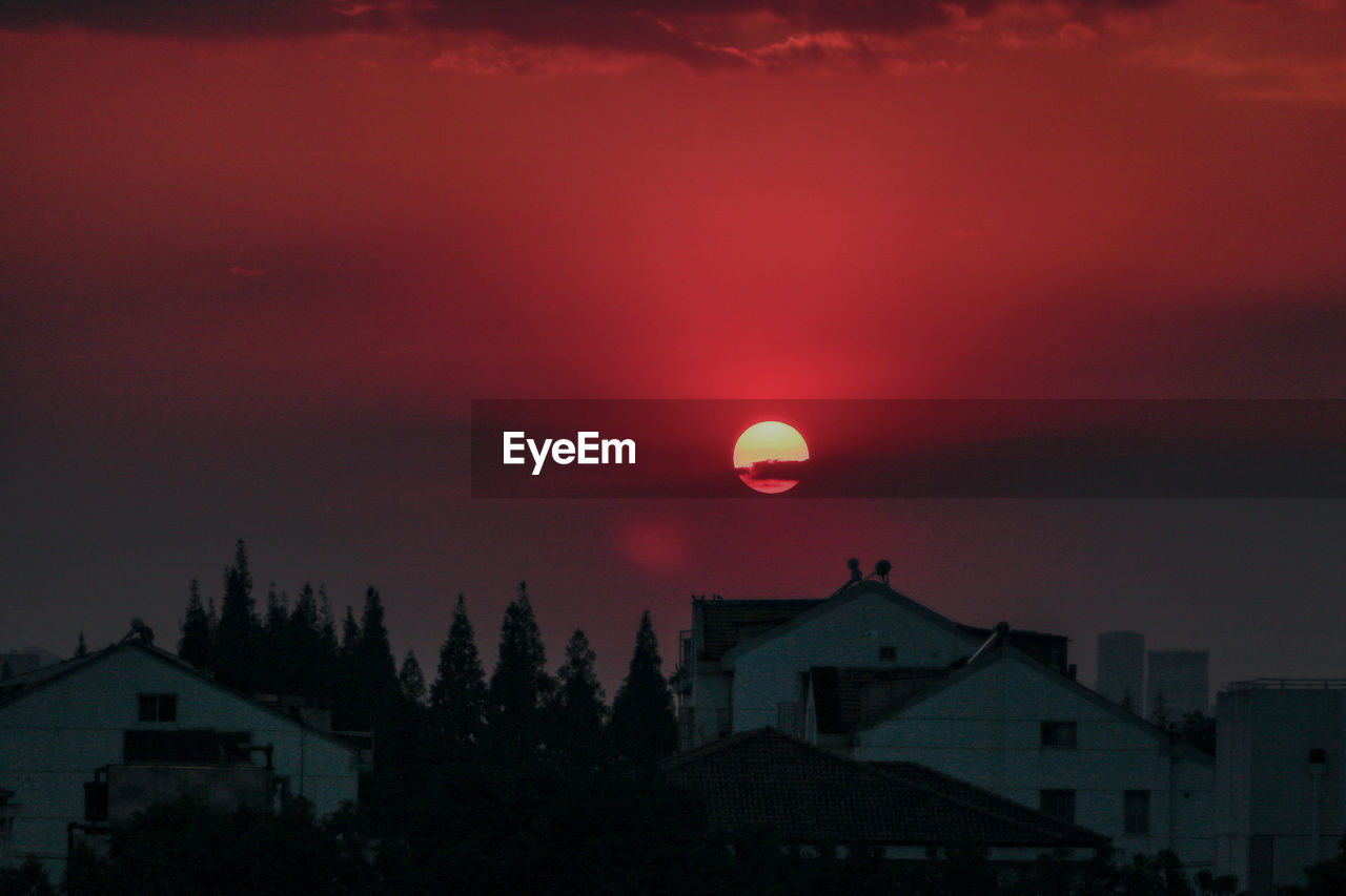 SILHOUETTE BUILDINGS AND TREES AGAINST ROMANTIC SKY AT SUNSET