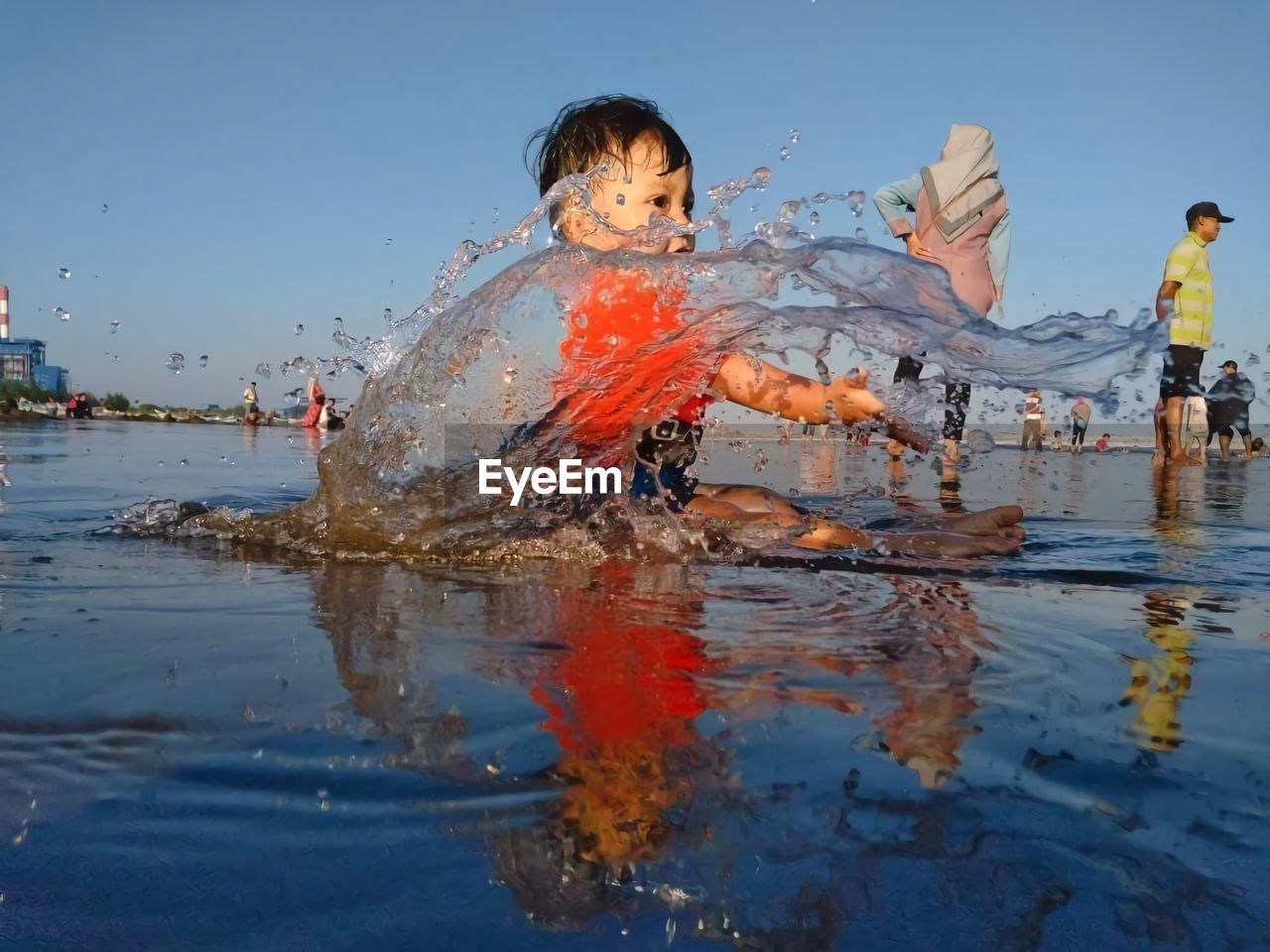 Cute boy playing in water against sky