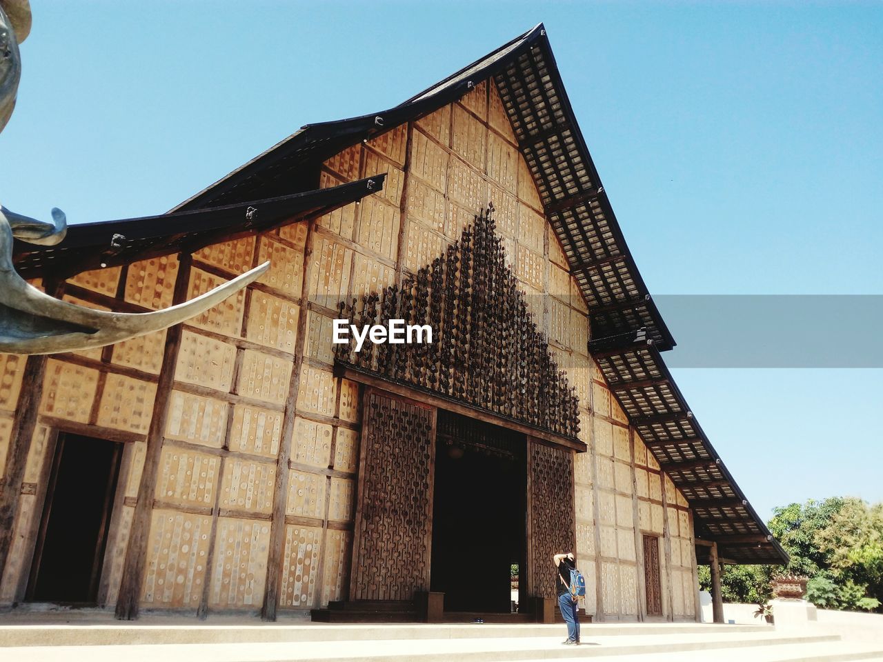 LOW ANGLE VIEW OF WOMAN WALKING AGAINST BUILDING