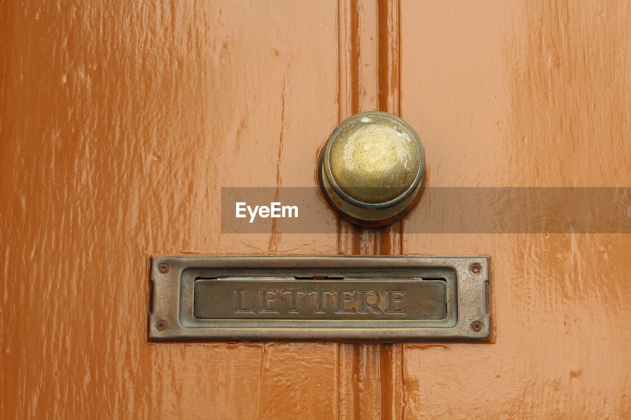 Close-up of mail slot on wooden door