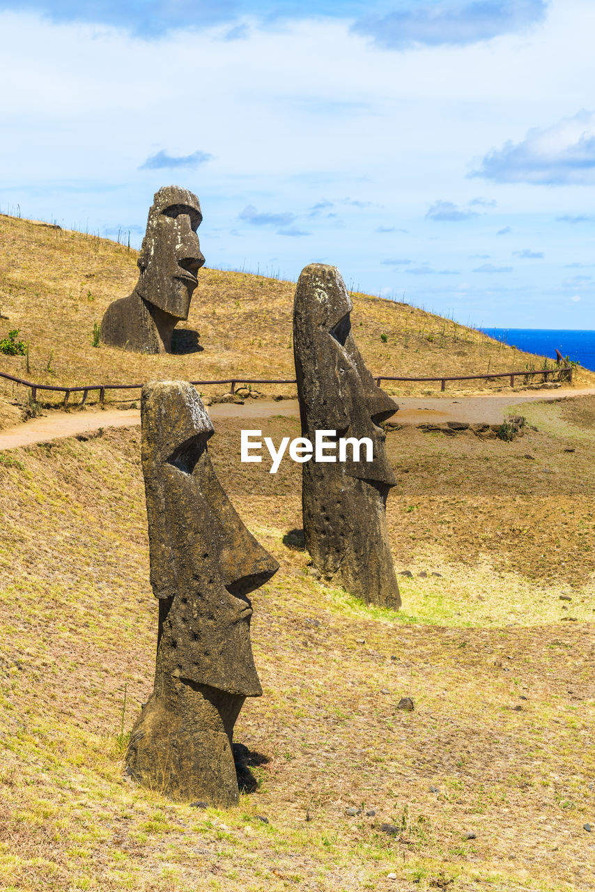 Stone sculptures on landscape against sky