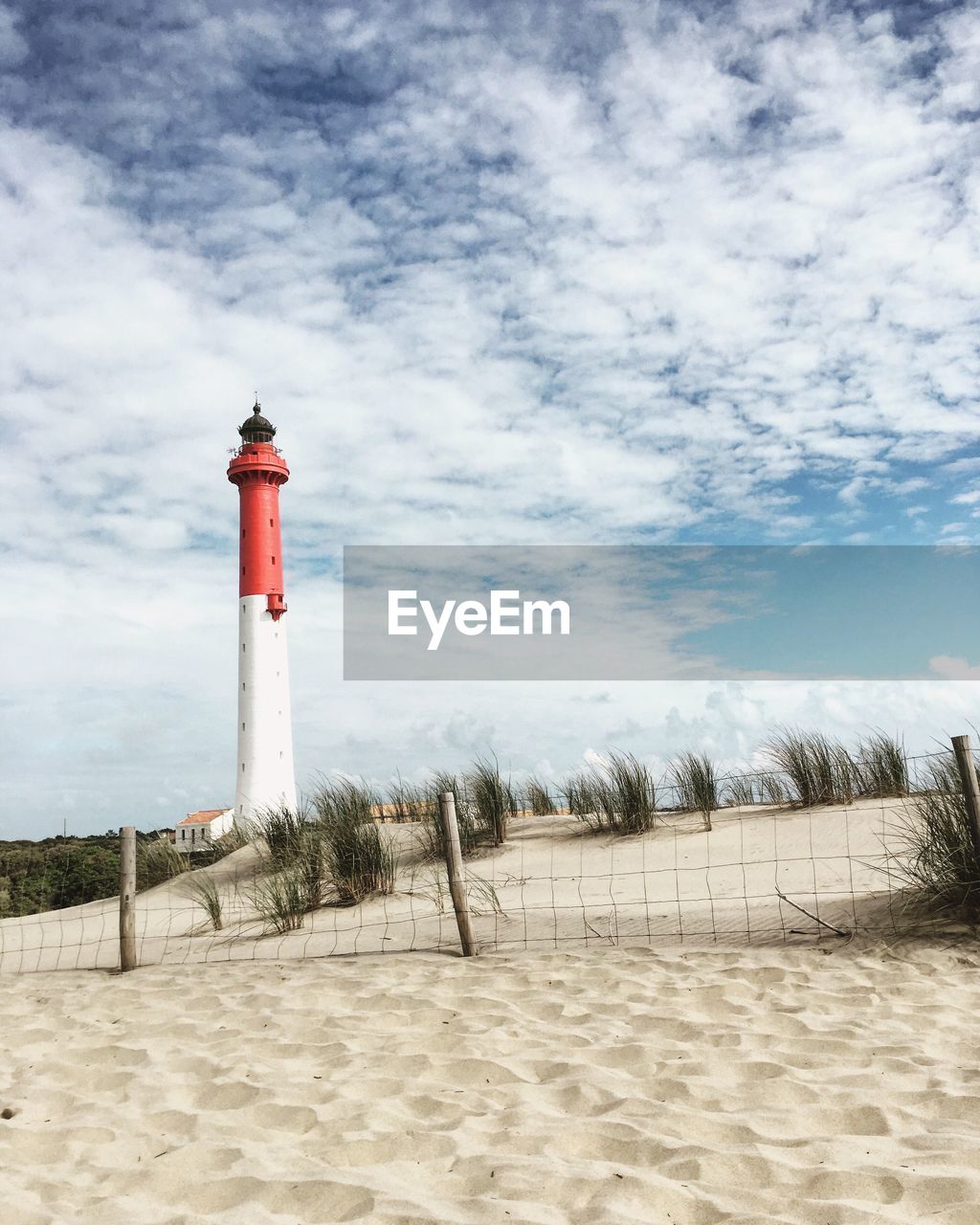 Lighthouse on beach against sky