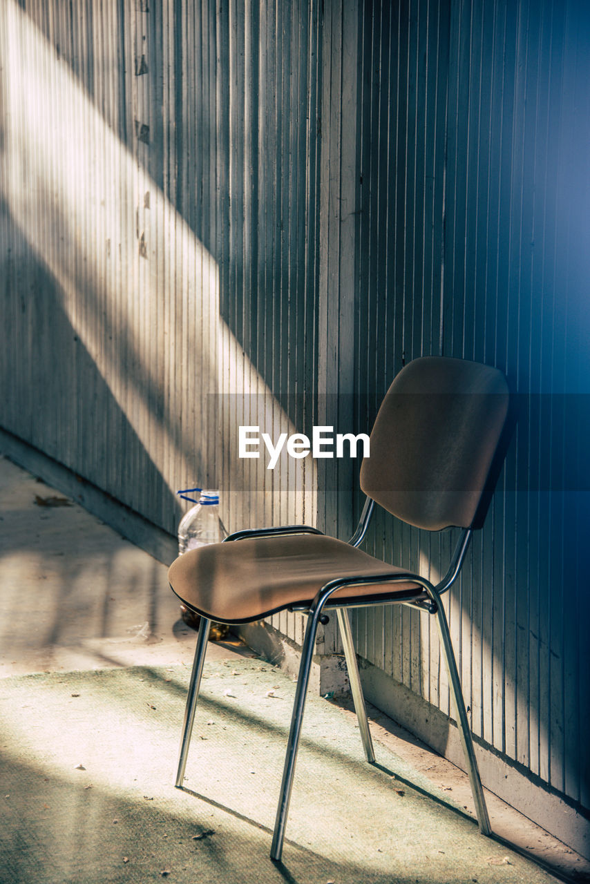 EMPTY CHAIR AND TABLE AGAINST WALL