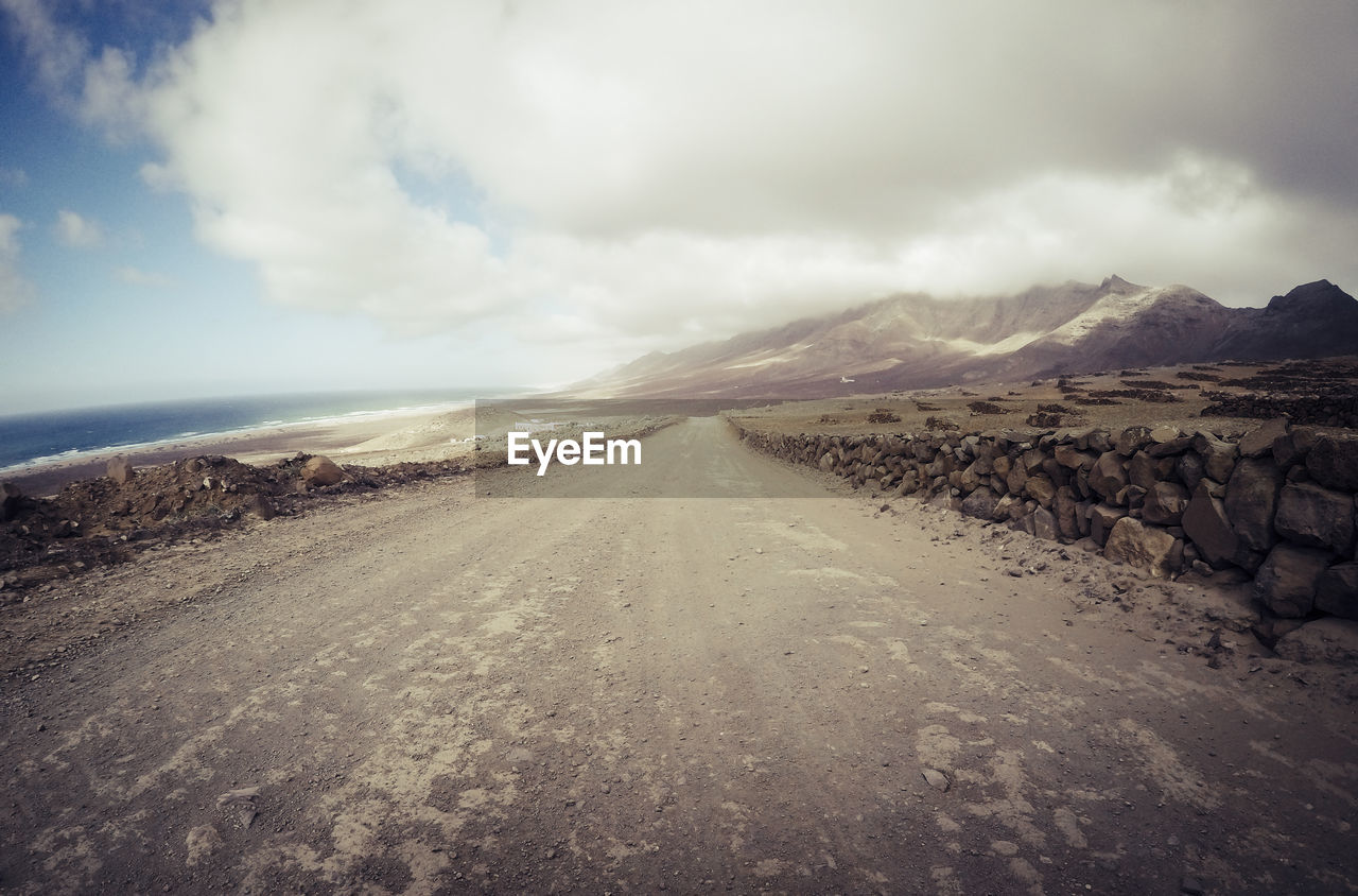 ROAD LEADING TOWARDS LAND AGAINST SKY