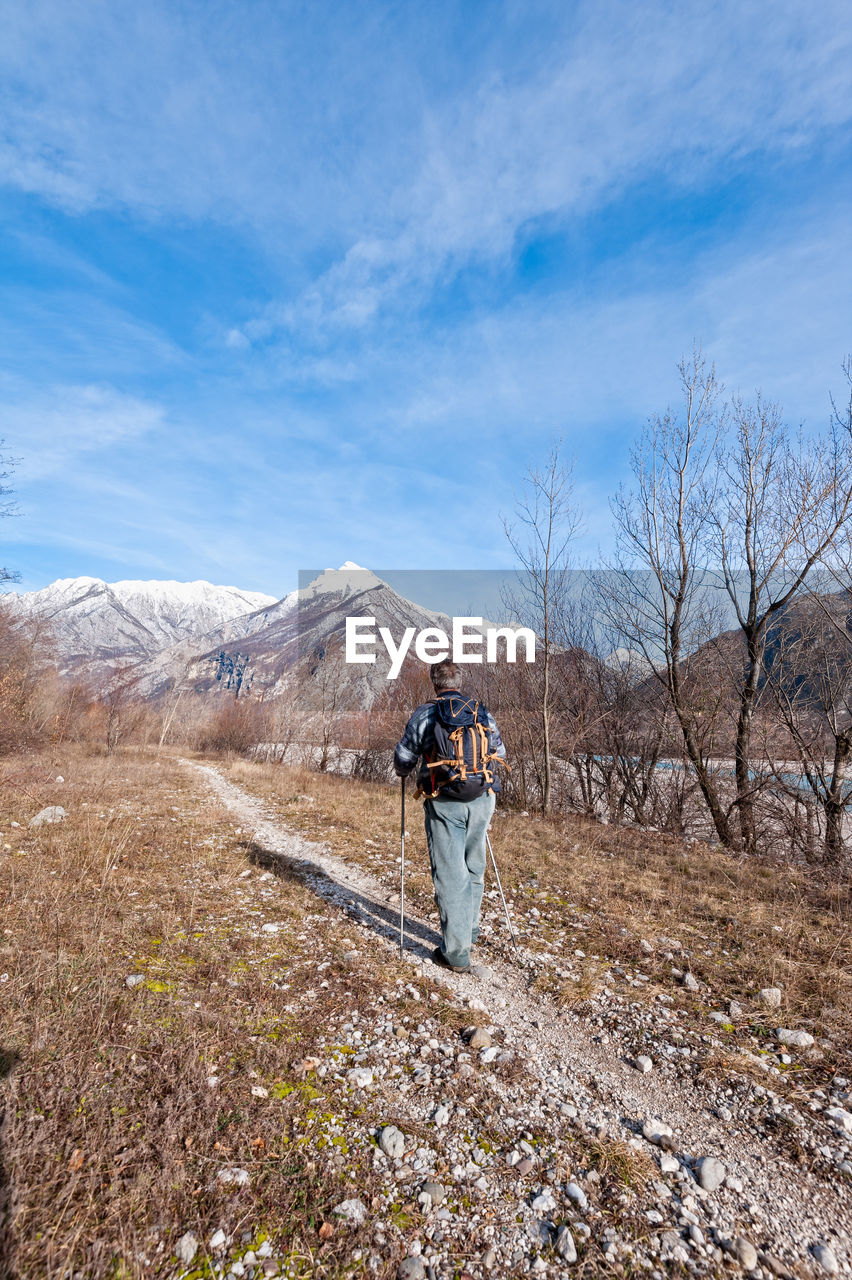 Rear view of man walking on land against sky