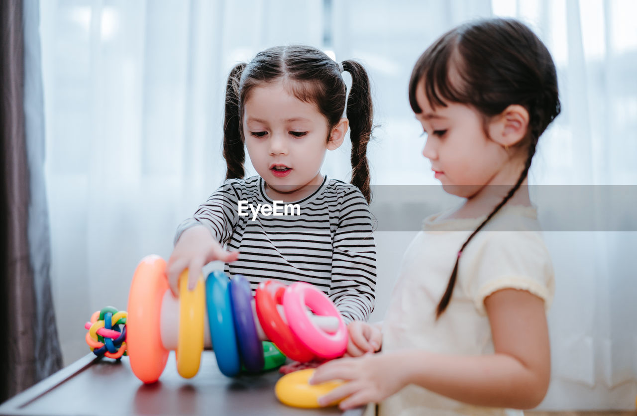 Sisters playing with multi colored toys at home