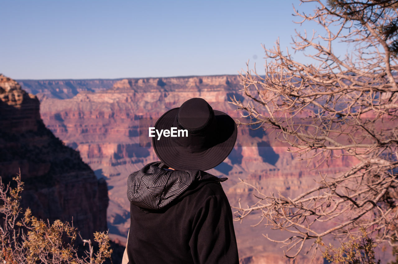 Man looking at a big ol' hole in the ground. sitting on the edge of the grand canyon