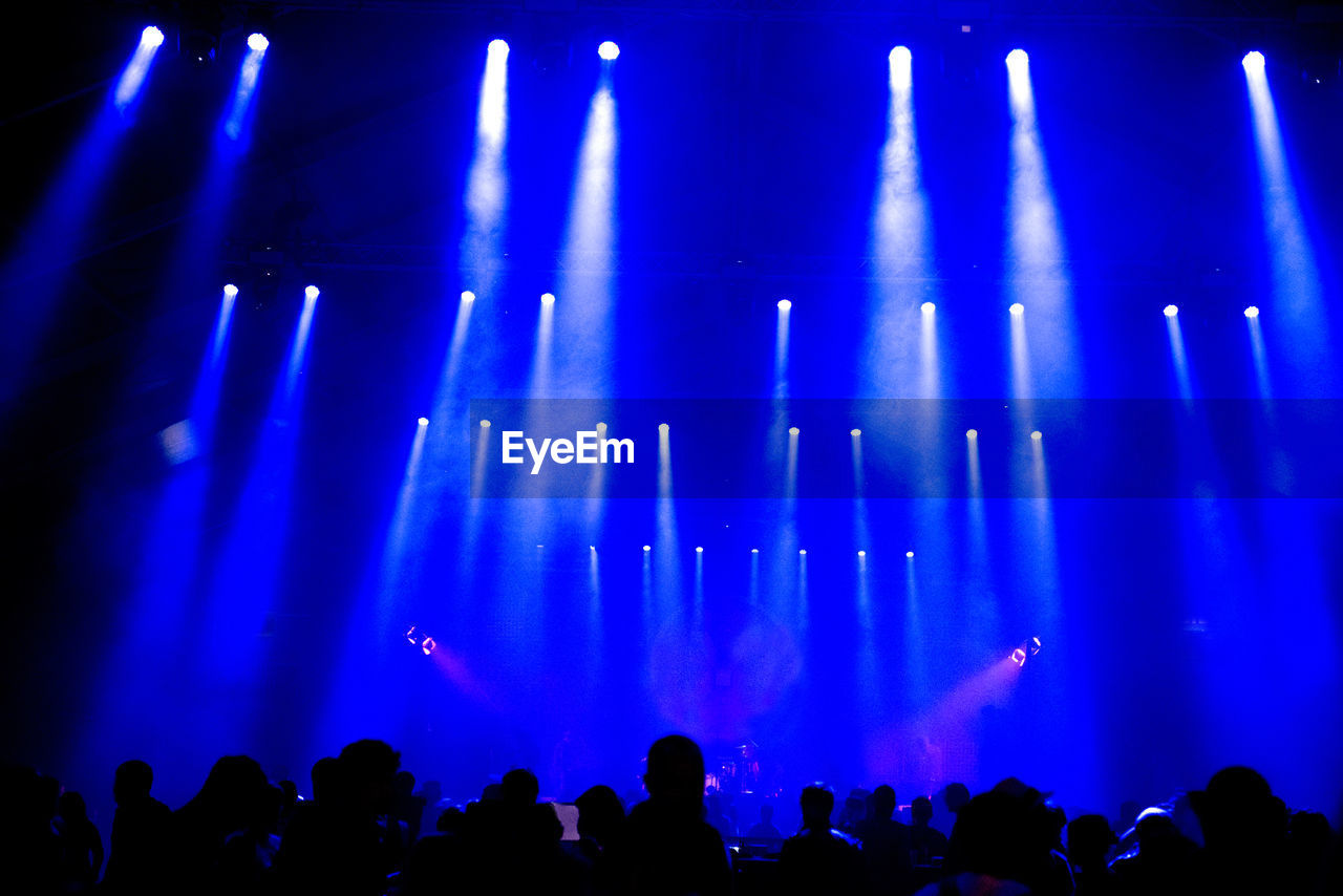 Crowd of people enjoying music festival. live concert and blue stage lights