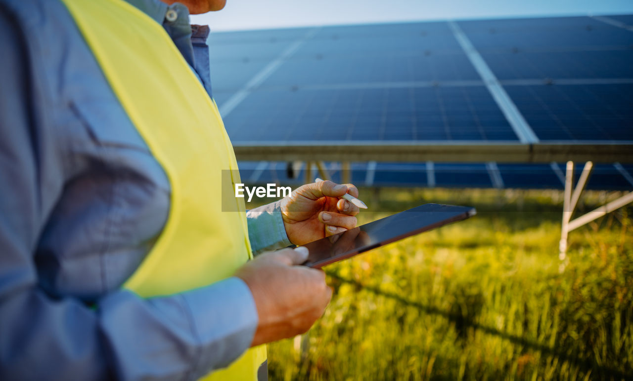 Inspector engineer man holding digital tablet working in solar panels power farm