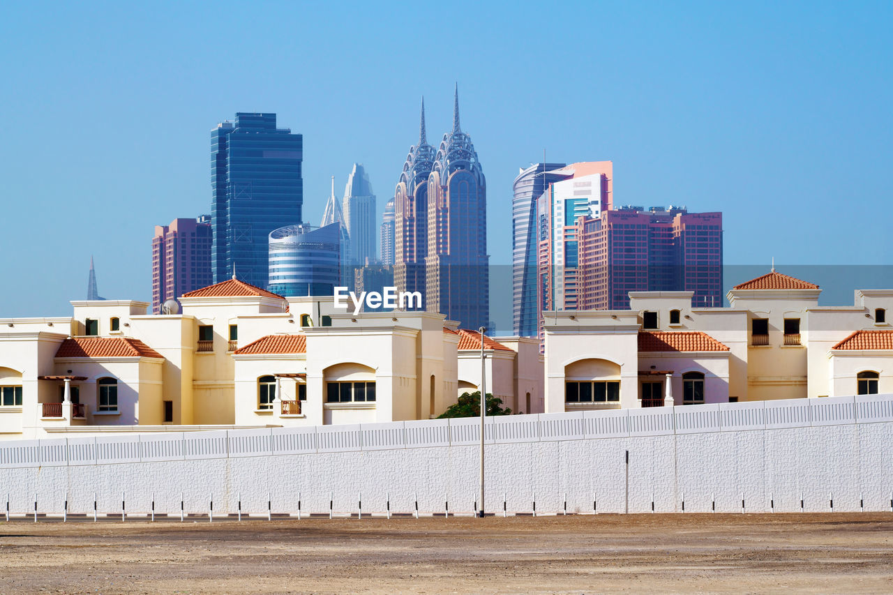 Buildings in city against clear blue sky