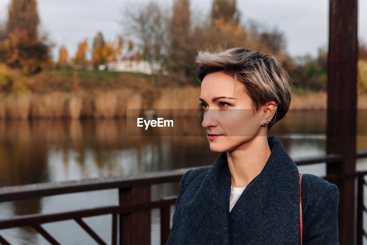 Woman look away against the backdrop of the river in autumn