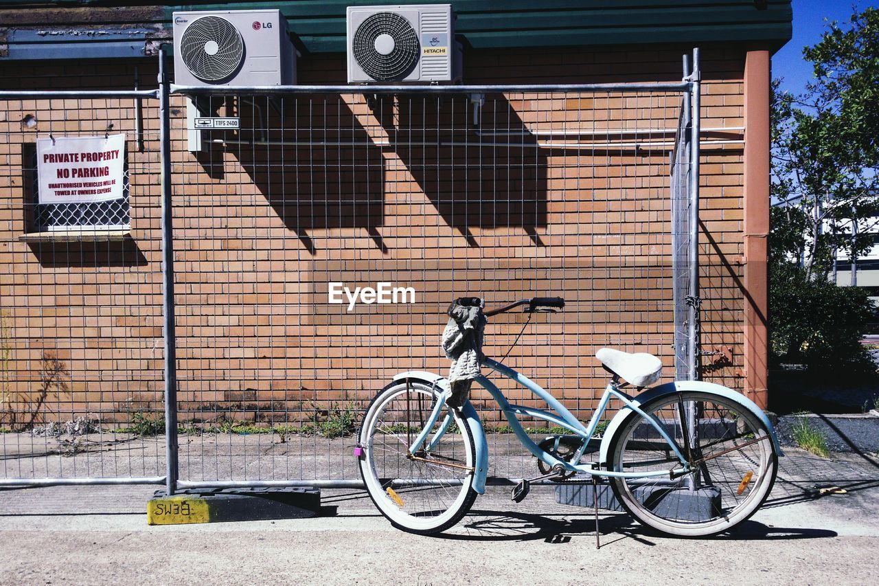 Bicycle by fence against building